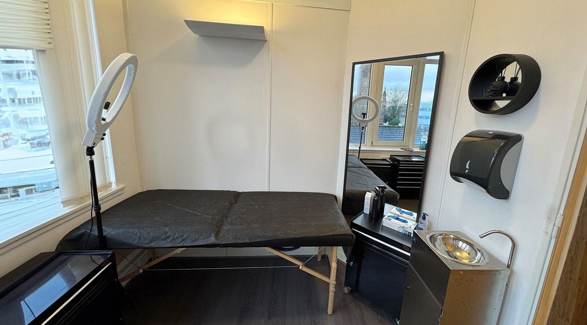 Modern interior of Valhalla Tattoo Studio, Kilmarnock, Scotland, GB, featuring a black treatment bed and ring light.