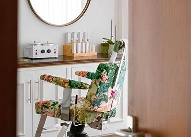 Elegant floral salon chair in Atelier Yurga, Chipping Norton, England, GB with beauty products on display.