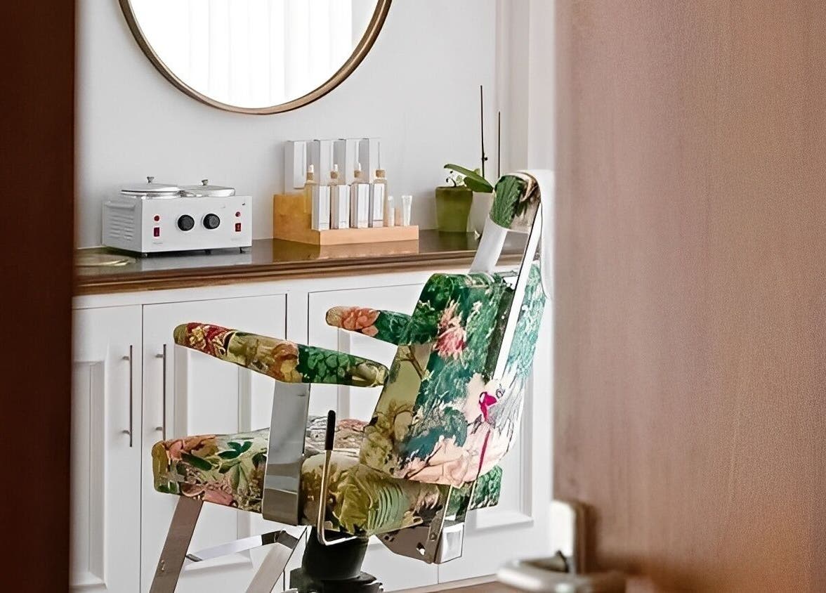 Elegant floral salon chair in Atelier Yurga, Chipping Norton, England, GB with beauty products on display.