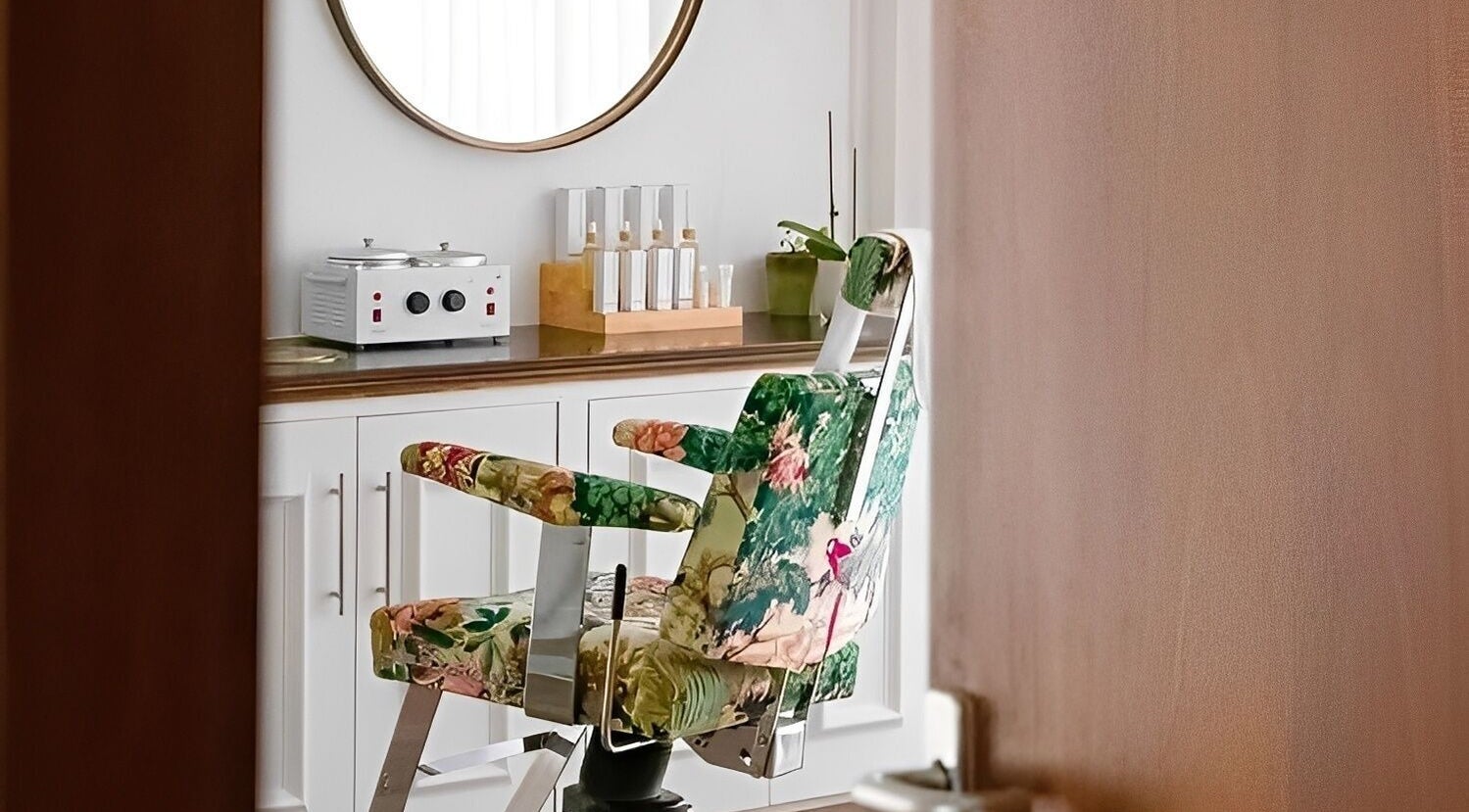 Elegant floral salon chair in Atelier Yurga, Chipping Norton, England, GB with beauty products on display.