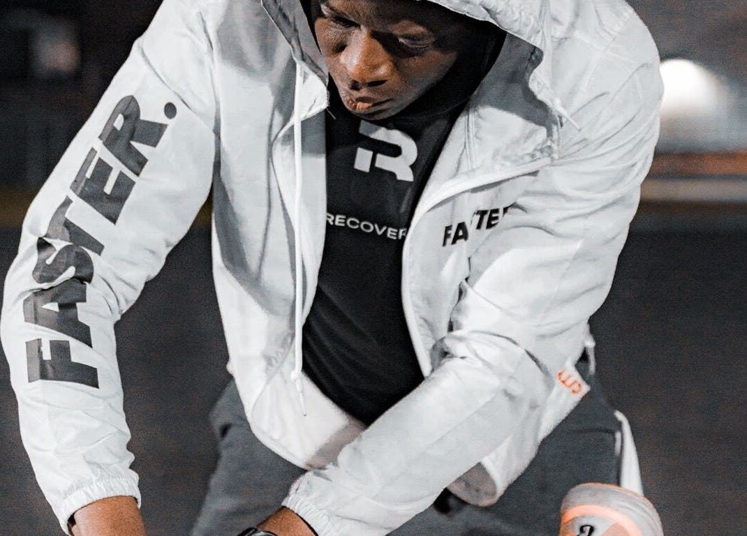 Focused athlete training outdoors in branded gear at Recover U Online (TeleHealth) in Houston, Texas, US.