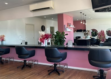 Interior of The Rosy Blonde, a stylish salon in Melbourne, Victoria, AU, with modern chairs and pink accents.