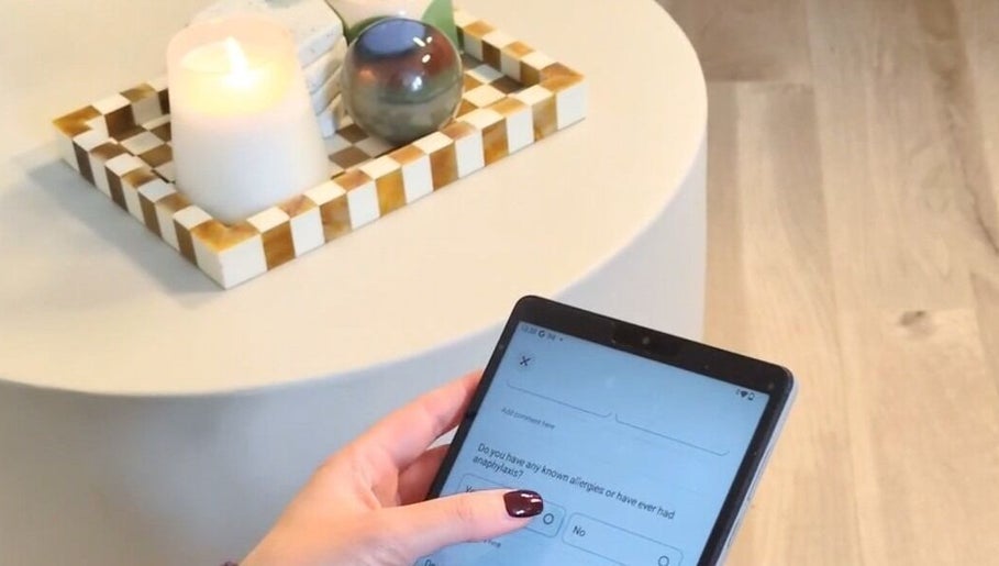 Person using tablet at Ellia | Advanced Aesthetics, Skin, SPMU, Orpington, England, GB. Candlelit ambiance.