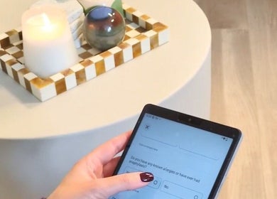 Person using tablet at Ellia | Advanced Aesthetics, Skin, SPMU, Orpington, England, GB. Candlelit ambiance.