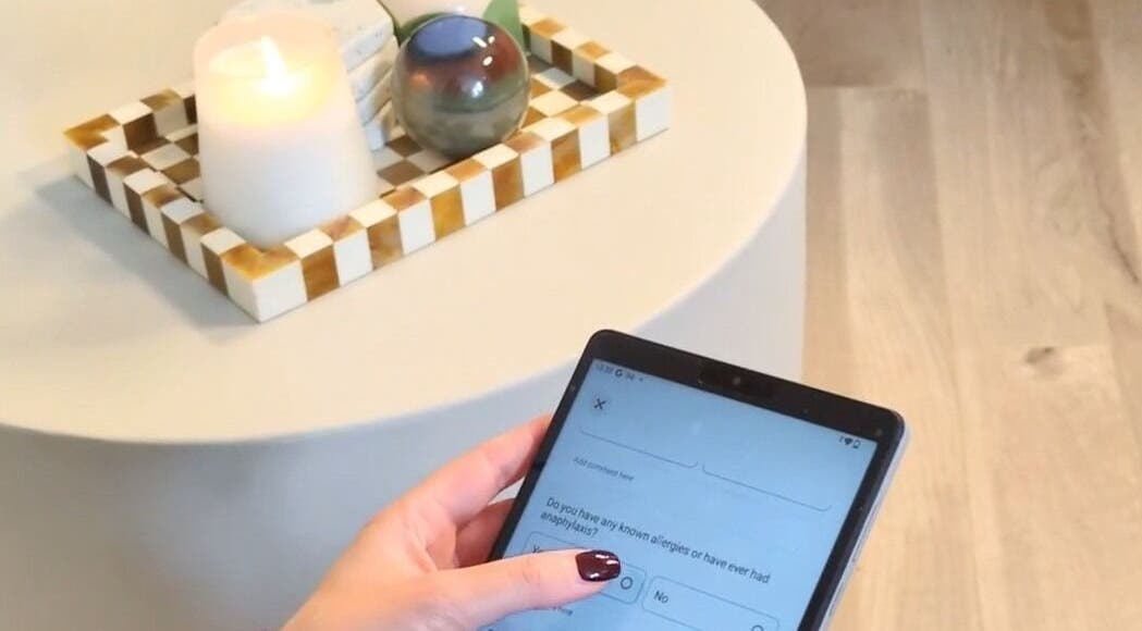 Person using tablet at Ellia | Advanced Aesthetics, Skin, SPMU, Orpington, England, GB. Candlelit ambiance.