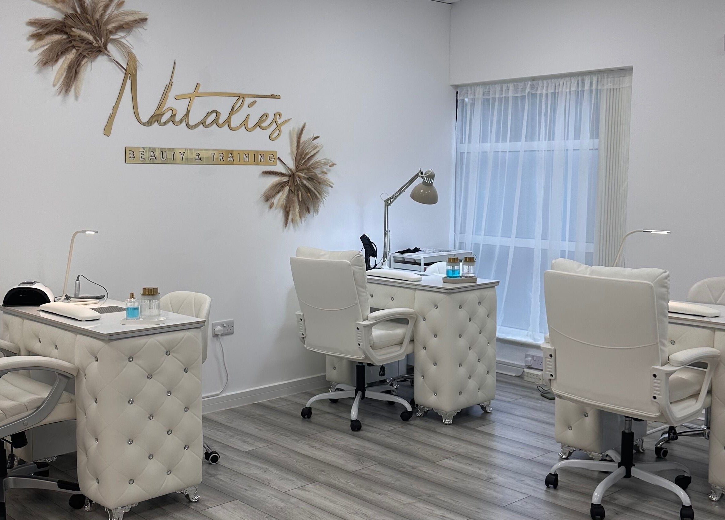 Chic nail stations at Natalies Beauty & Training in Cardiff, Wales, GB, featuring plush white chairs and stylish decor.
