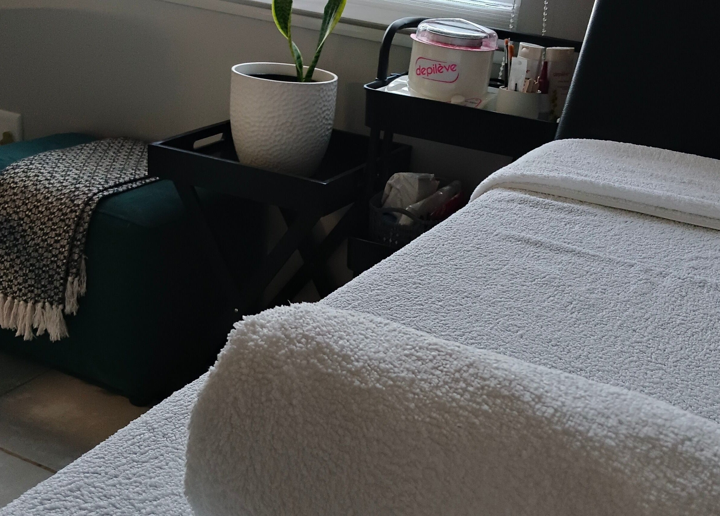 Relaxing corner at Scarletgold Beauty Salon, Johannesburg, Gauteng, ZA with a cozy massage table and potted plant.