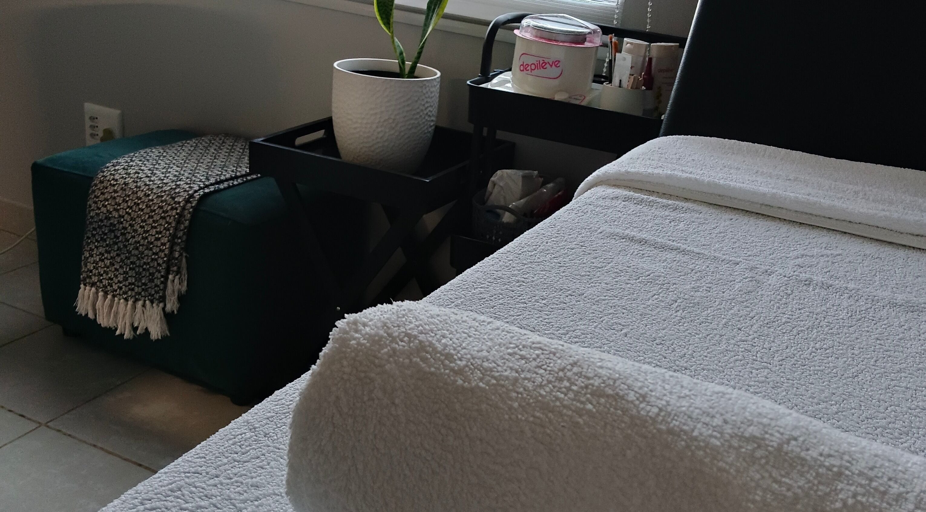Relaxing corner at Scarletgold Beauty Salon, Johannesburg, Gauteng, ZA with a cozy massage table and potted plant.