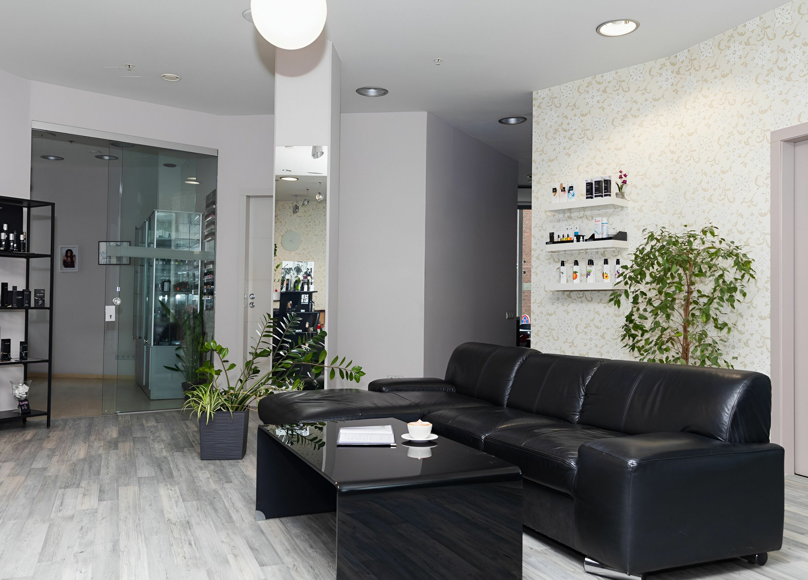 Elegant lounge area in LE STUDIO, Rīga, LV featuring black sofa, sleek decor, and plant accents.