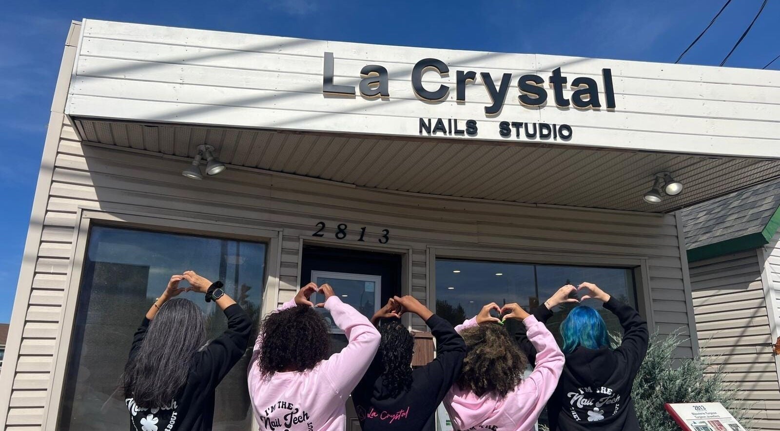 Team outside La Crystal Nail Studio, Ottawa, Ontario, CA showing heart gestures under the studio sign.