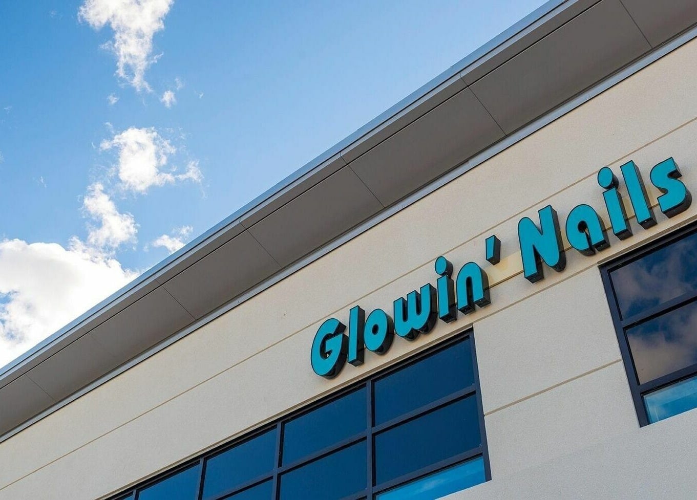 Close-up of Glowin’ Nails & Spa storefront in Aurora, Ontario, CA, showcasing modern design and clear blue sky.