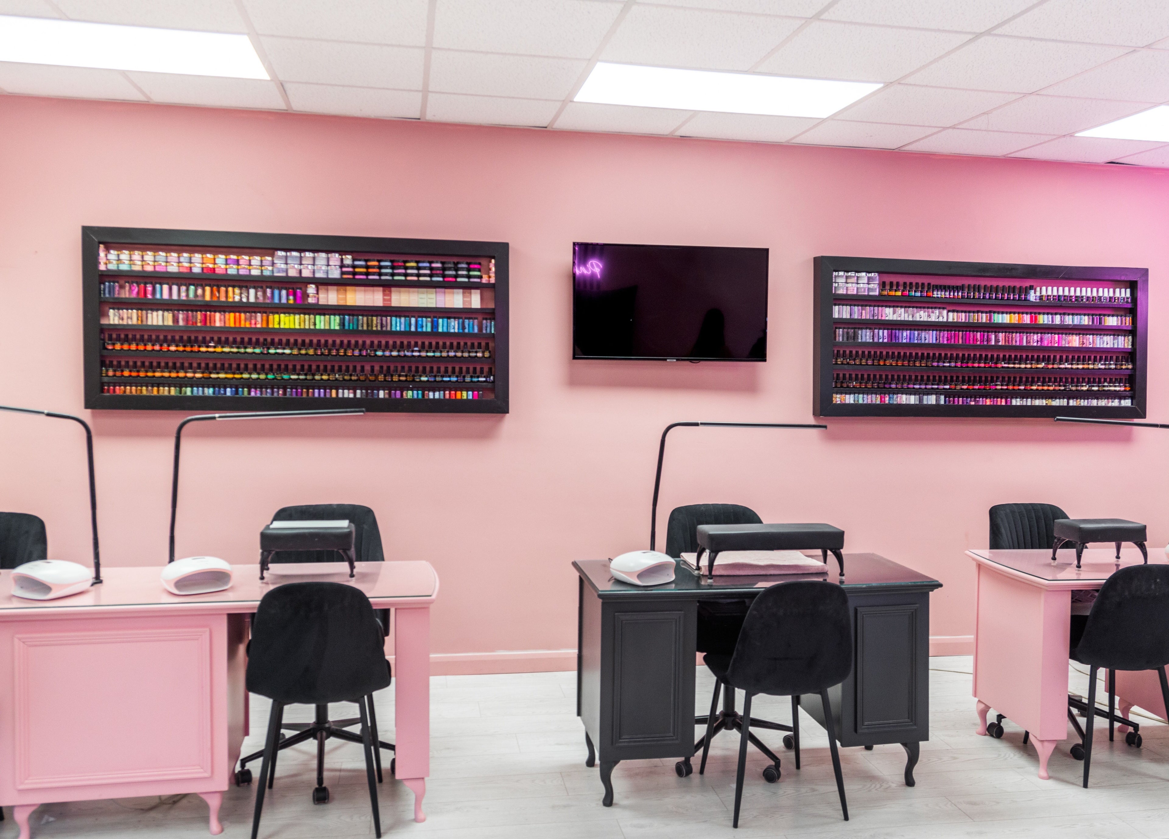 Manicure stations at The Pink Room in Warrington, England, GB with pink walls and nail polish display.