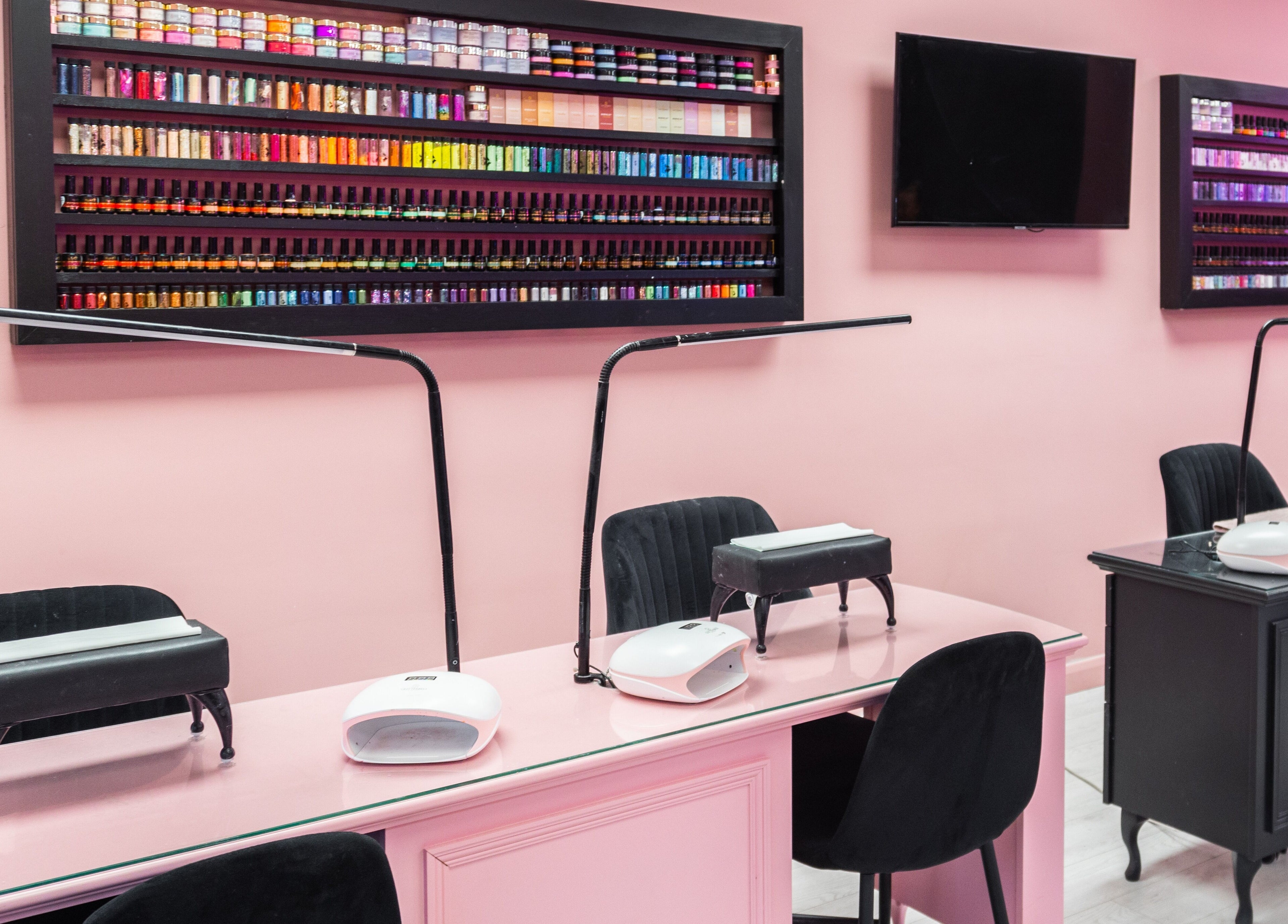 The Pink Room nail salon in Warrington, England showcases vibrant nail polish wall and chic workstations.