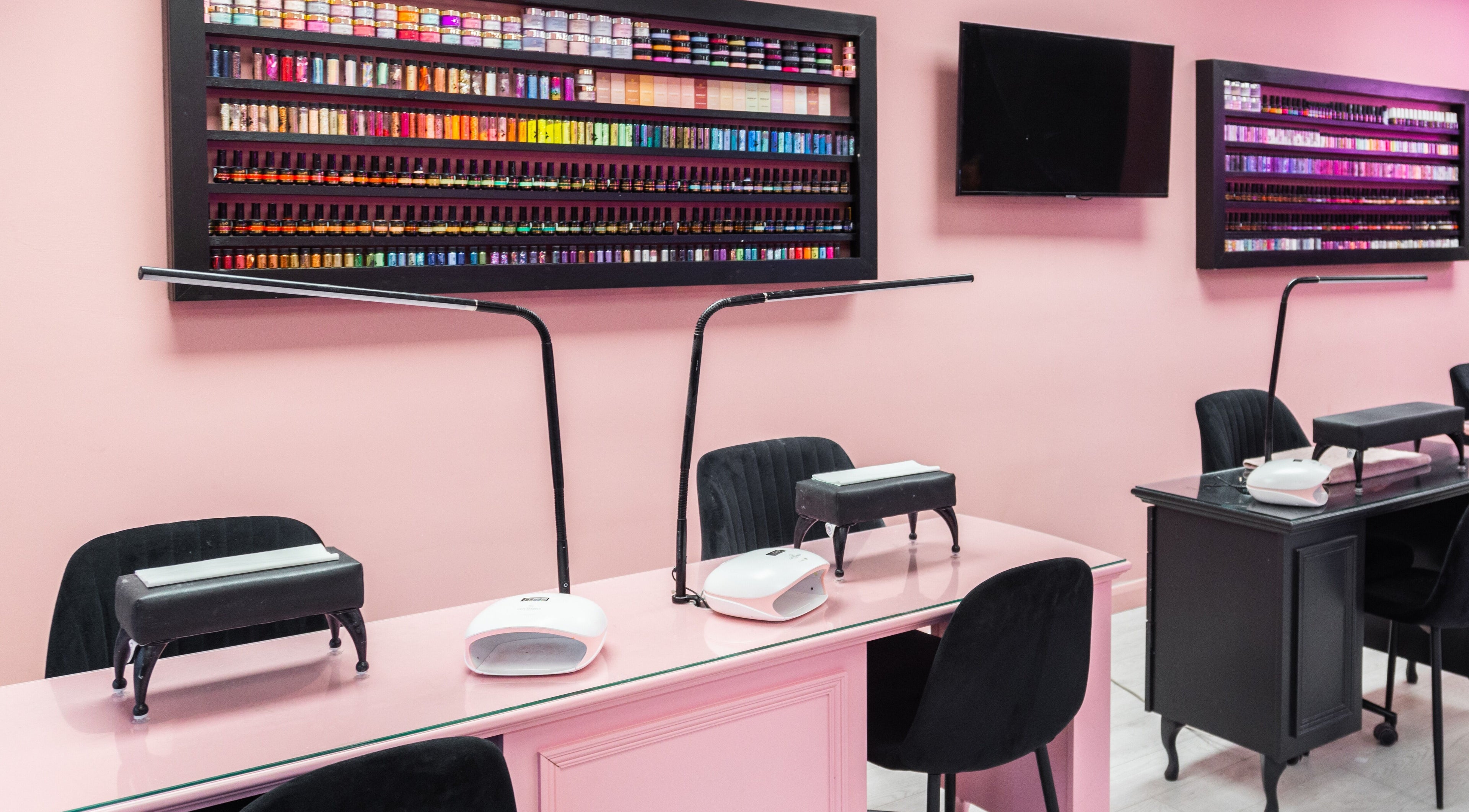 The Pink Room nail salon in Warrington, England showcases vibrant nail polish wall and chic workstations.