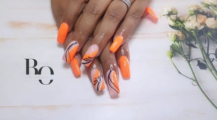 Vibrant orange nail art at Black Orchid Beauty Bar, Johannesburg, Gauteng, ZA, complemented by floral decor.