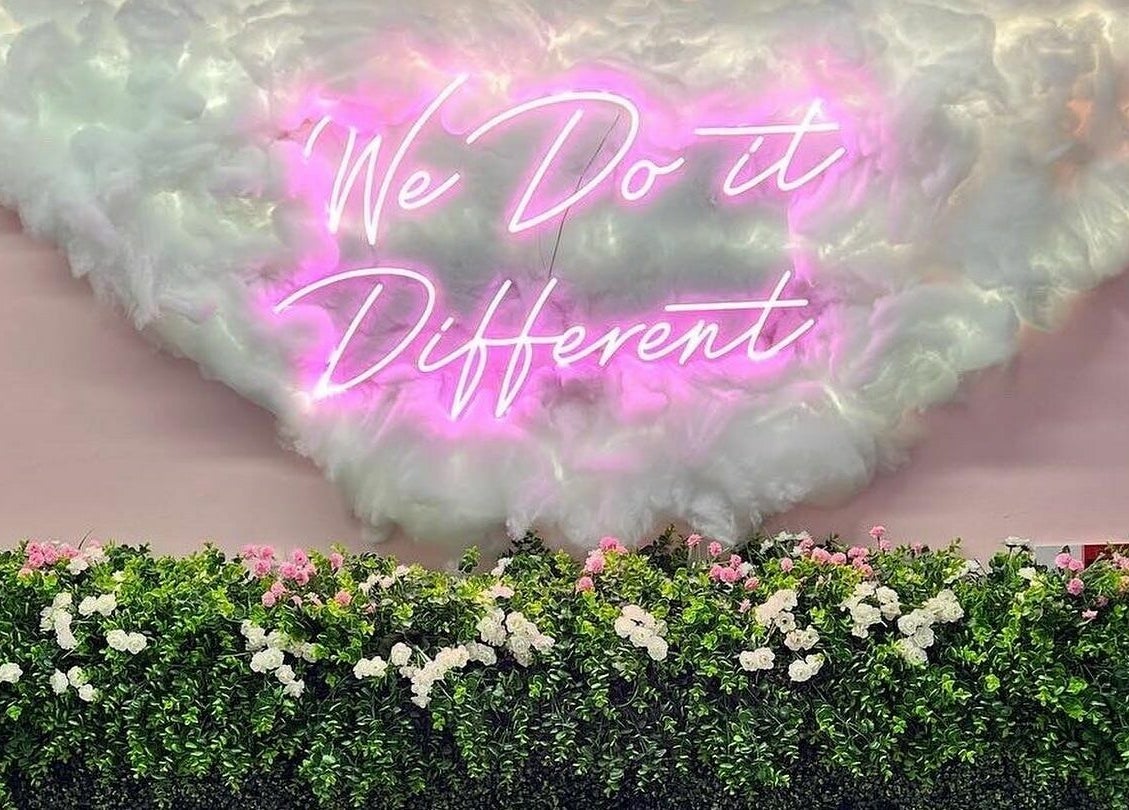 Neon sign 'We Do it Different' on floral backdrop at Head Hunters Salon Pontefract, Pontefract, England, GB.