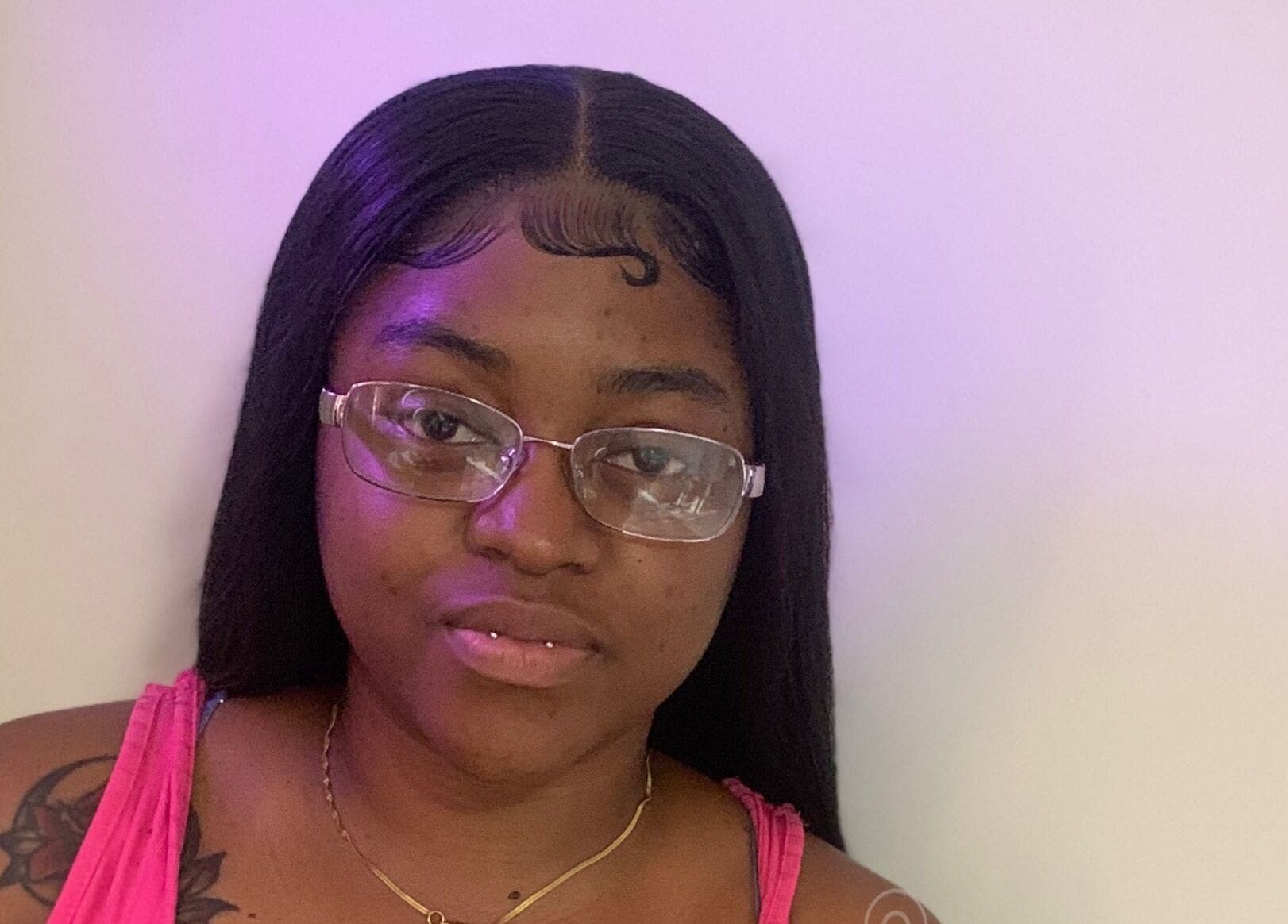 Smiling woman at Beauty Cellar 242, Nassau, New Providence, with stylish hairstyle and glasses.