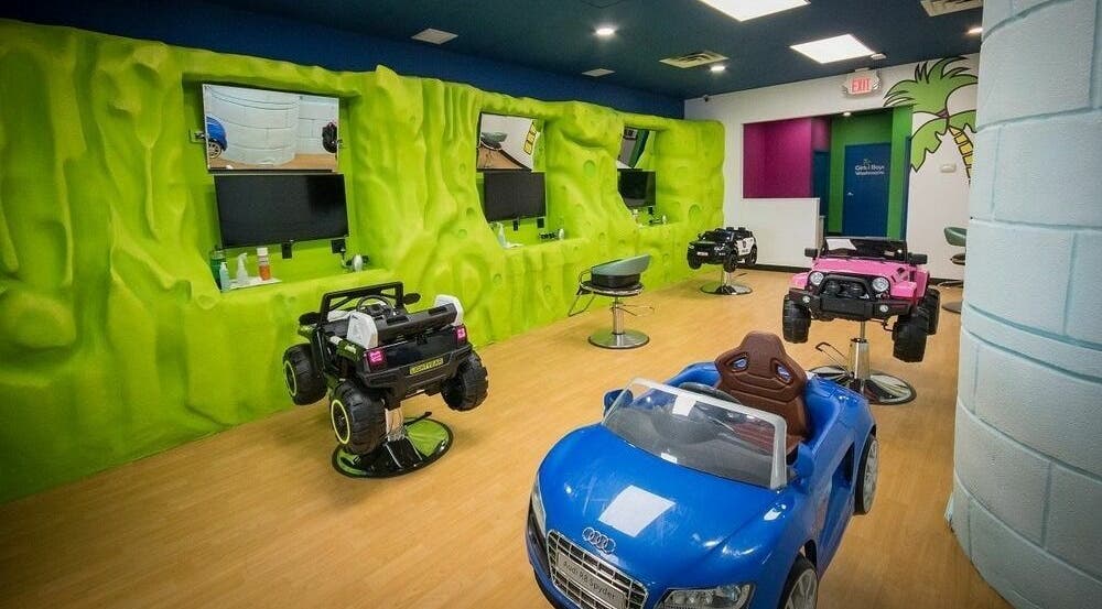 Vibrant kids salon at Hair Tropics, Calgary, Alberta, CA with playful car chairs and green jungle walls.