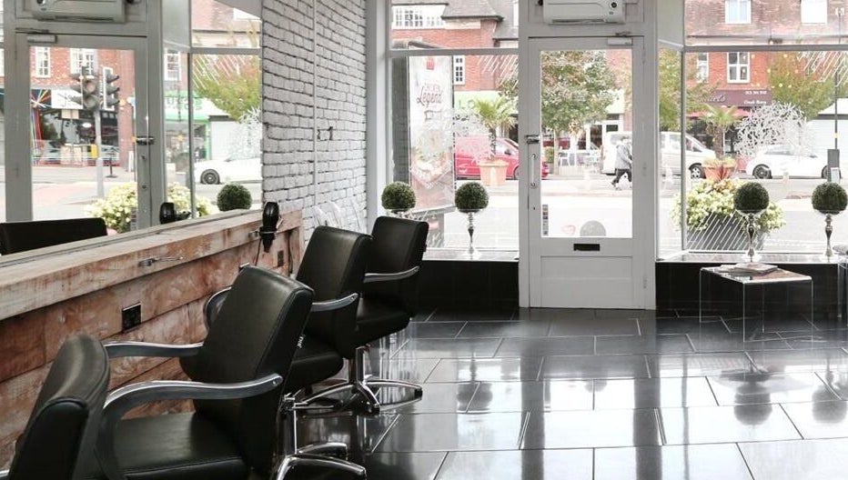 Stylish interior of Chair-Sam Slater salon, Birmingham, England, GB with modern seating and street view.