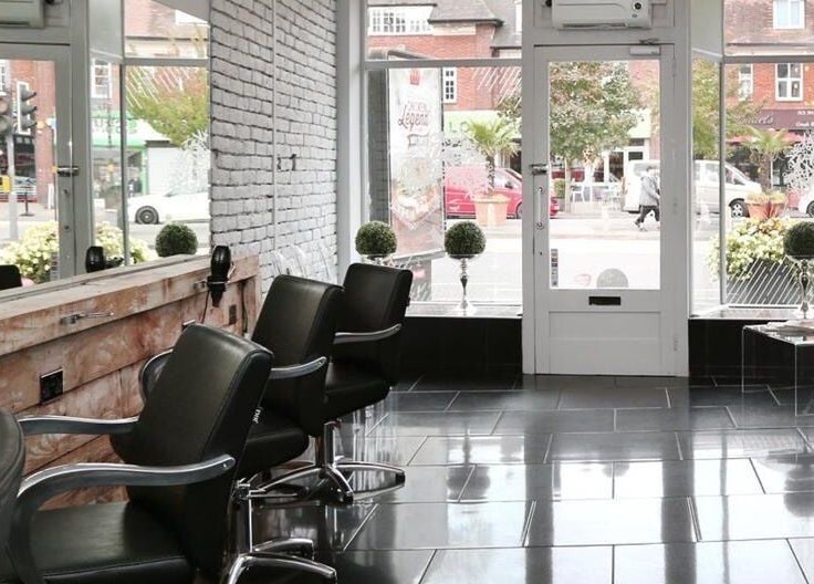 Stylish interior of Chair-Sam Slater salon, Birmingham, England, GB with modern seating and street view.