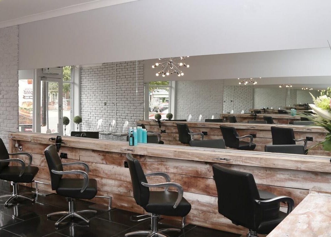 Modern salon interior at Chair-Sam Slater, Birmingham, England, GB. Black chairs, rustic decor, sleek mirrors.