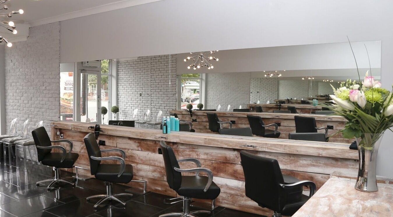 Modern salon interior at Chair-Sam Slater, Birmingham, England, GB. Black chairs, rustic decor, sleek mirrors.