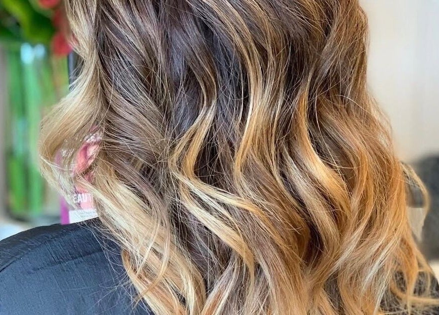Elegant wavy hairstyle at Chair-Sam Slater, Birmingham, England, GB with golden brown highlights.
