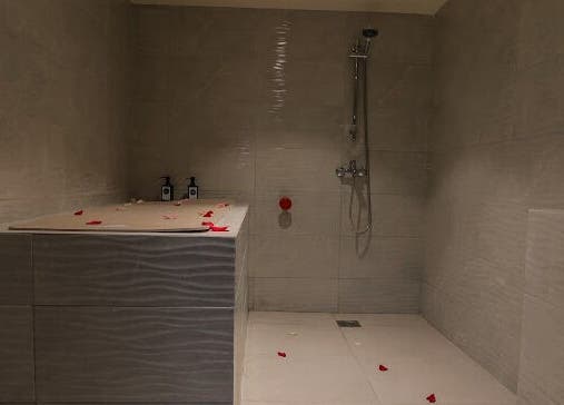 Relaxing shower area at Hairpage in Saar, BH, with tiled walls and flower petals.