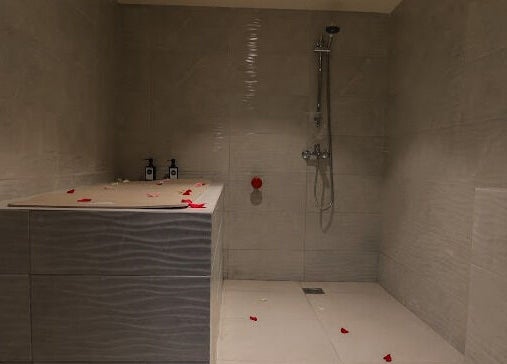 Relaxing shower area at Hairpage in Saar, BH, with tiled walls and flower petals.