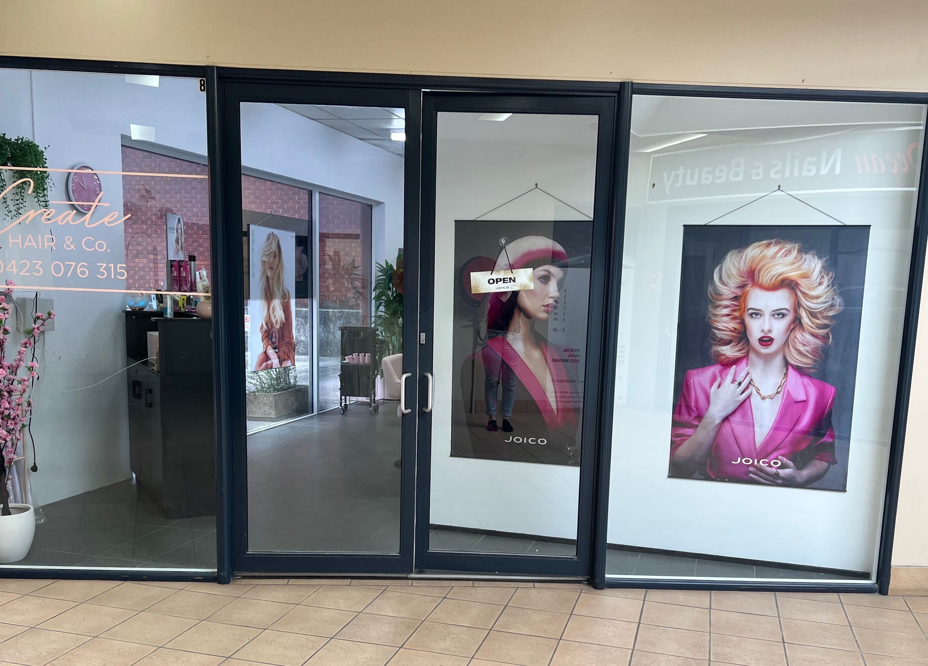 Create Hair & Co entrance in Corrimal, New South Wales, AU, showcasing vibrant salon posters and modern decor.
