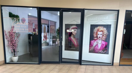 Create Hair & Co entrance in Corrimal, New South Wales, AU, showcasing vibrant salon posters and modern decor.