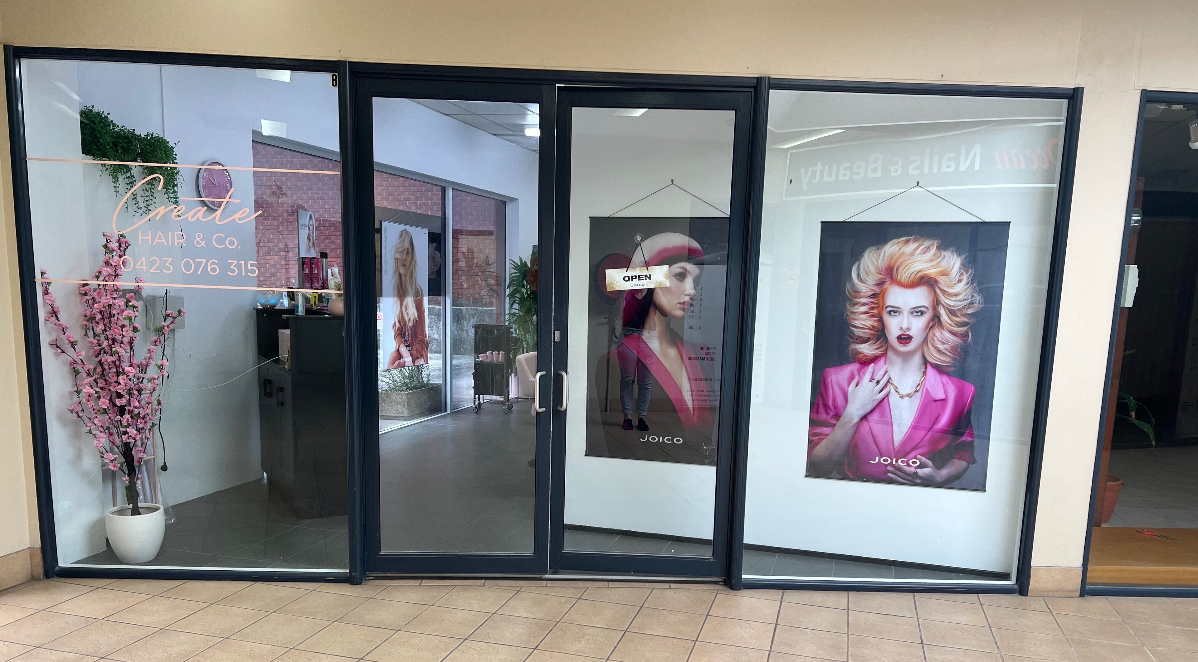 Create Hair & Co entrance in Corrimal, New South Wales, AU, showcasing vibrant salon posters and modern decor.
