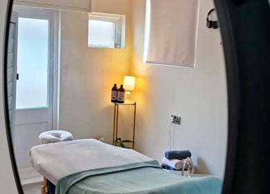 Tranquil massage room at Renew Massage Therapies, Ottery Saint Mary, England, with soft lighting and cozy bed.