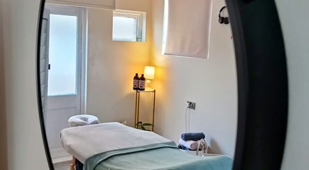 Tranquil massage room at Renew Massage Therapies, Ottery Saint Mary, England, with soft lighting and cozy bed.