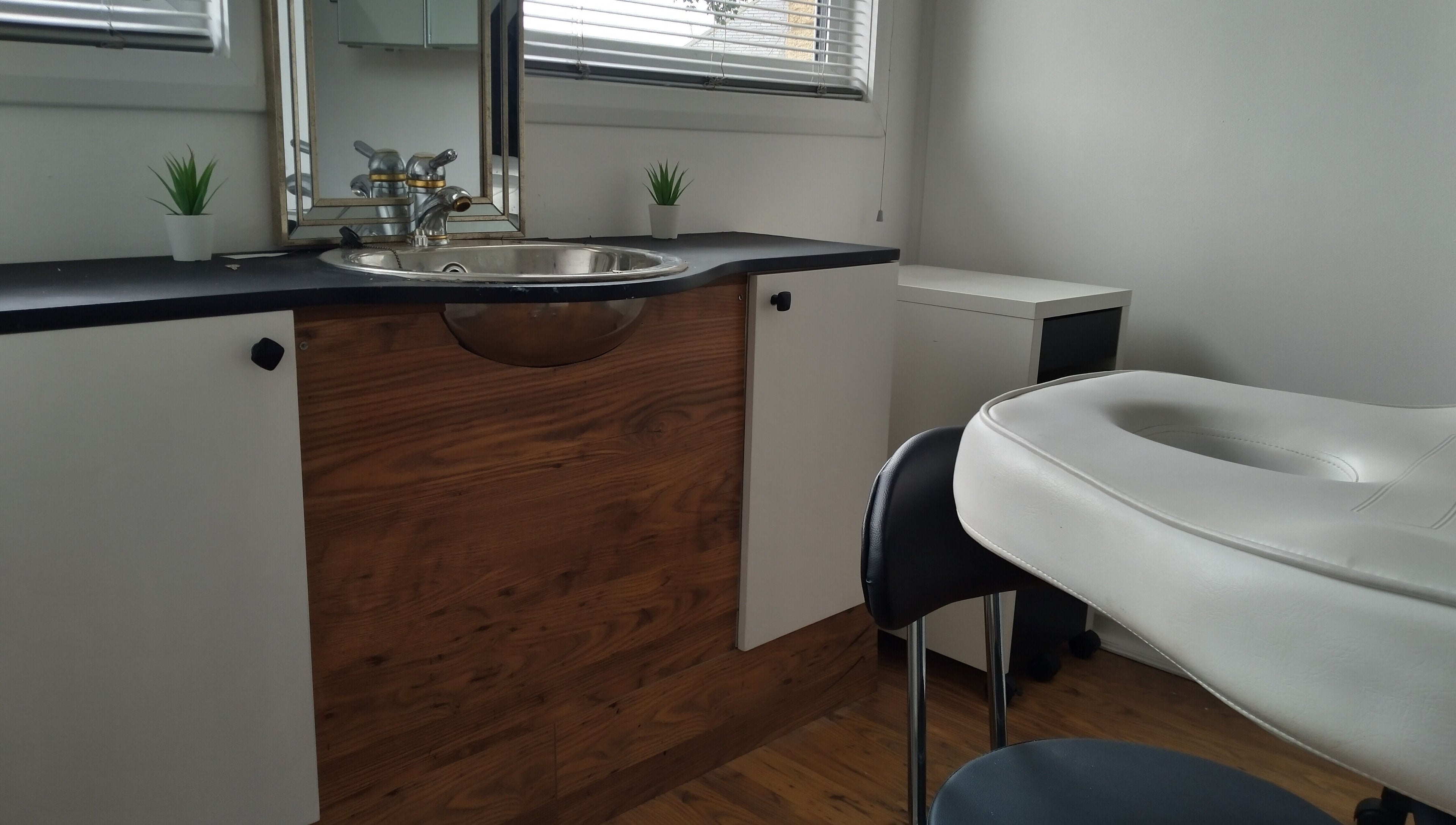 Elegant massage room at Lothian Massage & Acupuncture, Tranent, Scotland, GB with wooden decor and white furniture.