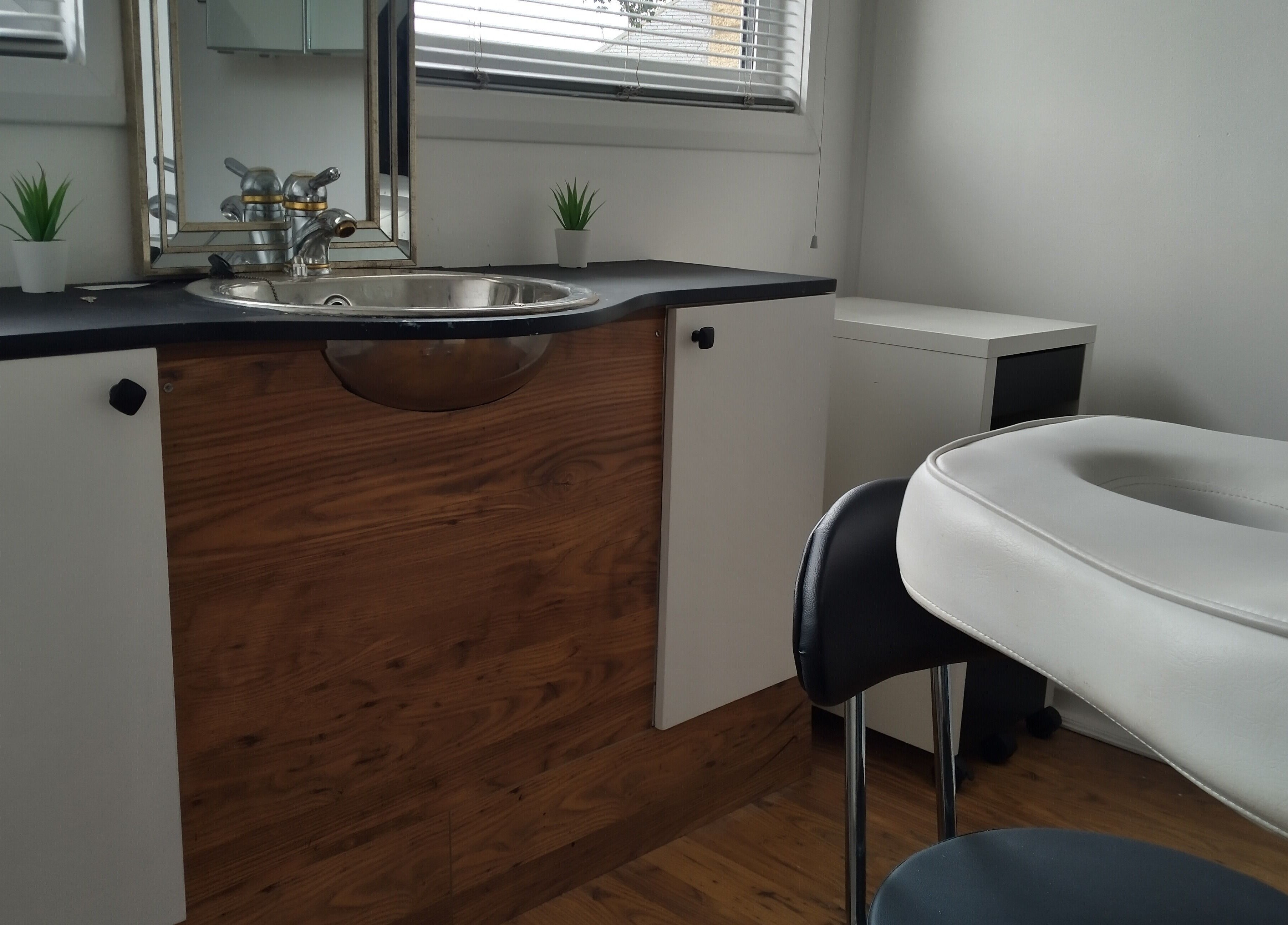 Elegant massage room at Lothian Massage & Acupuncture, Tranent, Scotland, GB with wooden decor and white furniture.