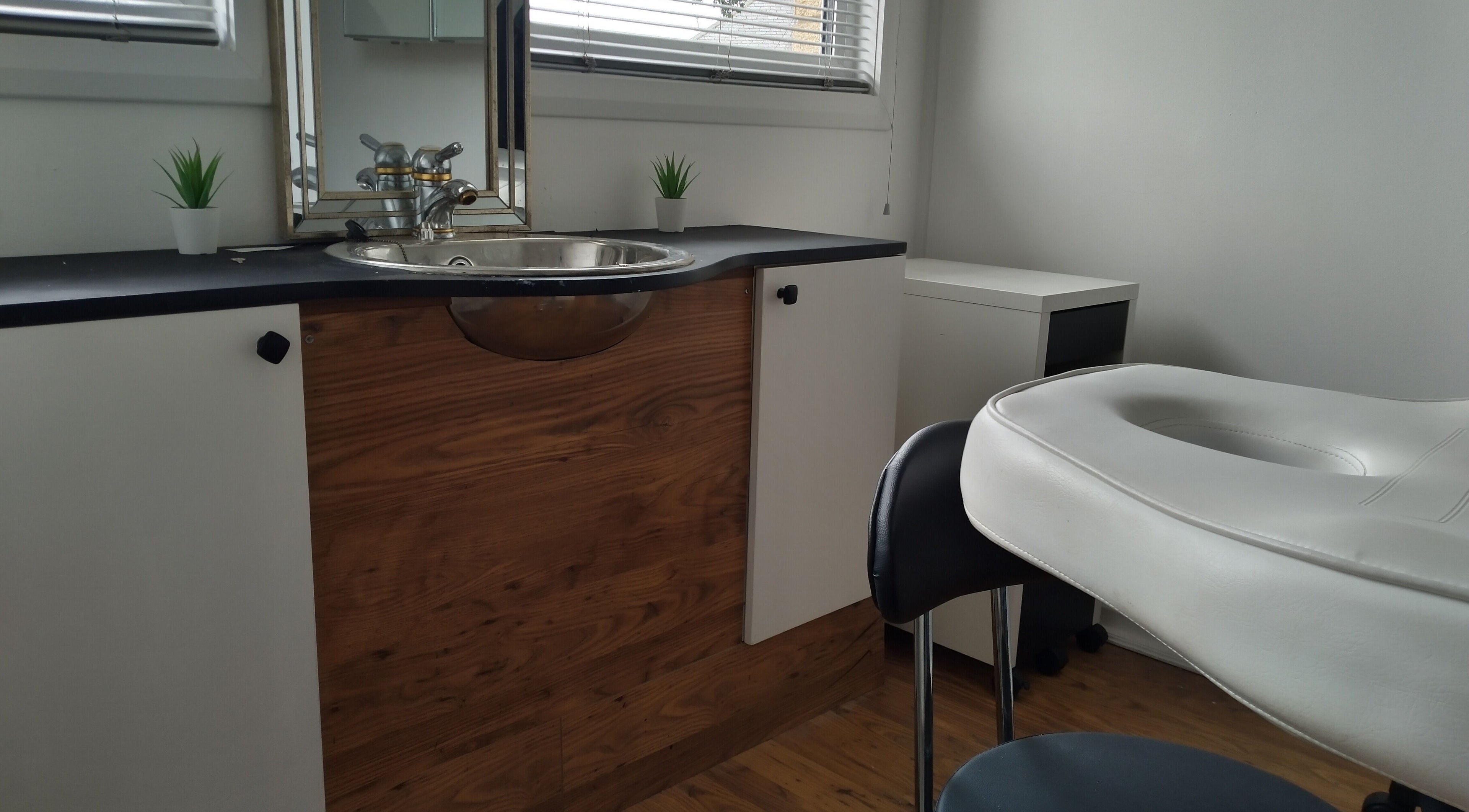 Elegant massage room at Lothian Massage & Acupuncture, Tranent, Scotland, GB with wooden decor and white furniture.