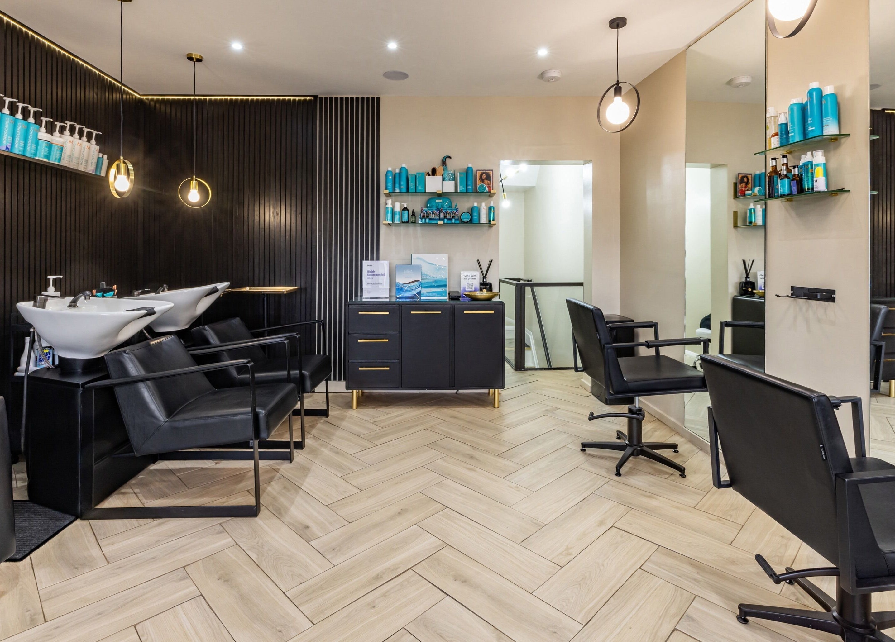 Modern salon interior at ATH Studios, Croydon, England, GB. Elegant hairdresser chairs and products displayed.
