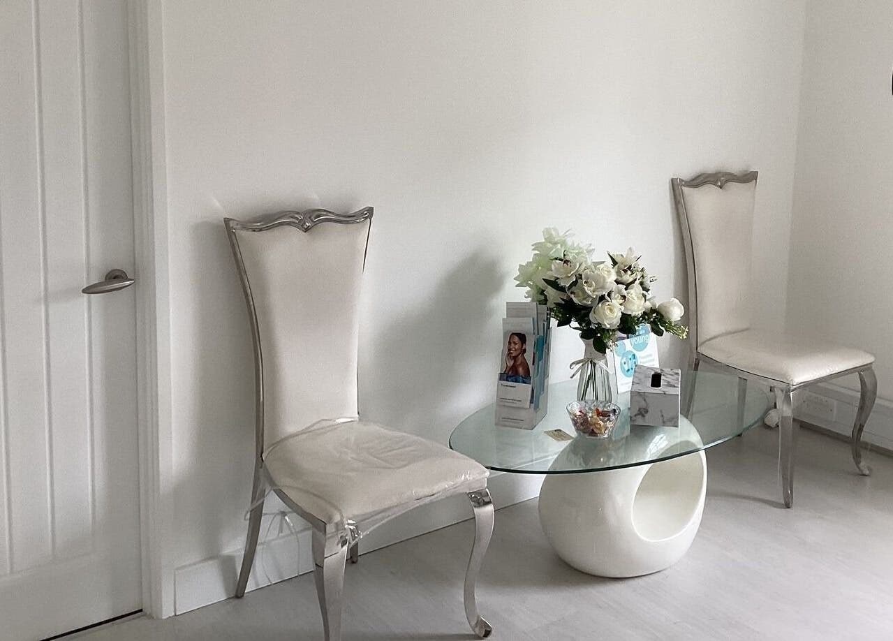 Chic waiting area at Laserlite Aesthetic Clinic, Croydon, England, GB, featuring white chairs and a glass table.