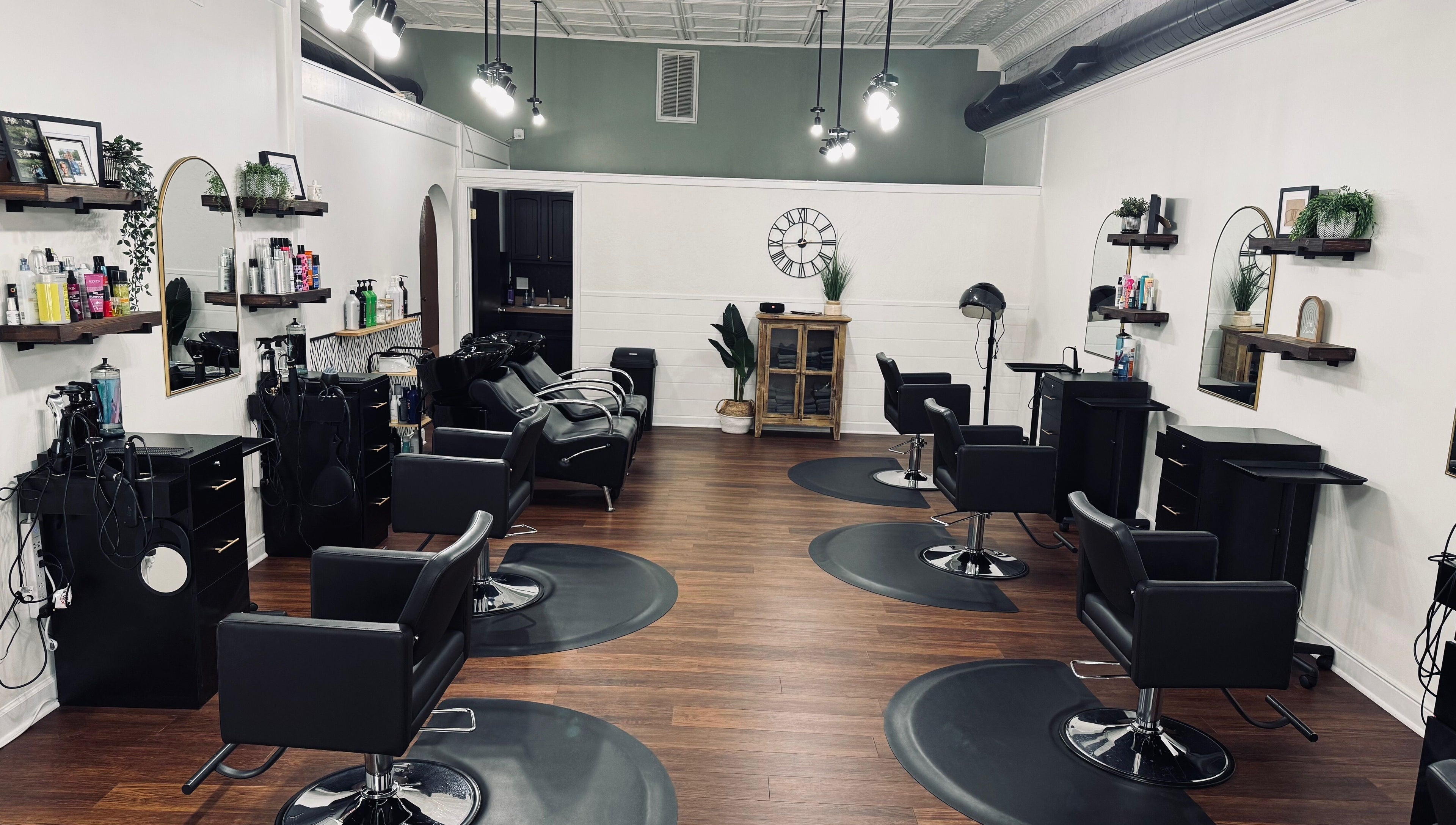 Modern interior of Rooted Salon in Eaton Rapids, Michigan, US, showcasing sleek black styling chairs and mirrors.