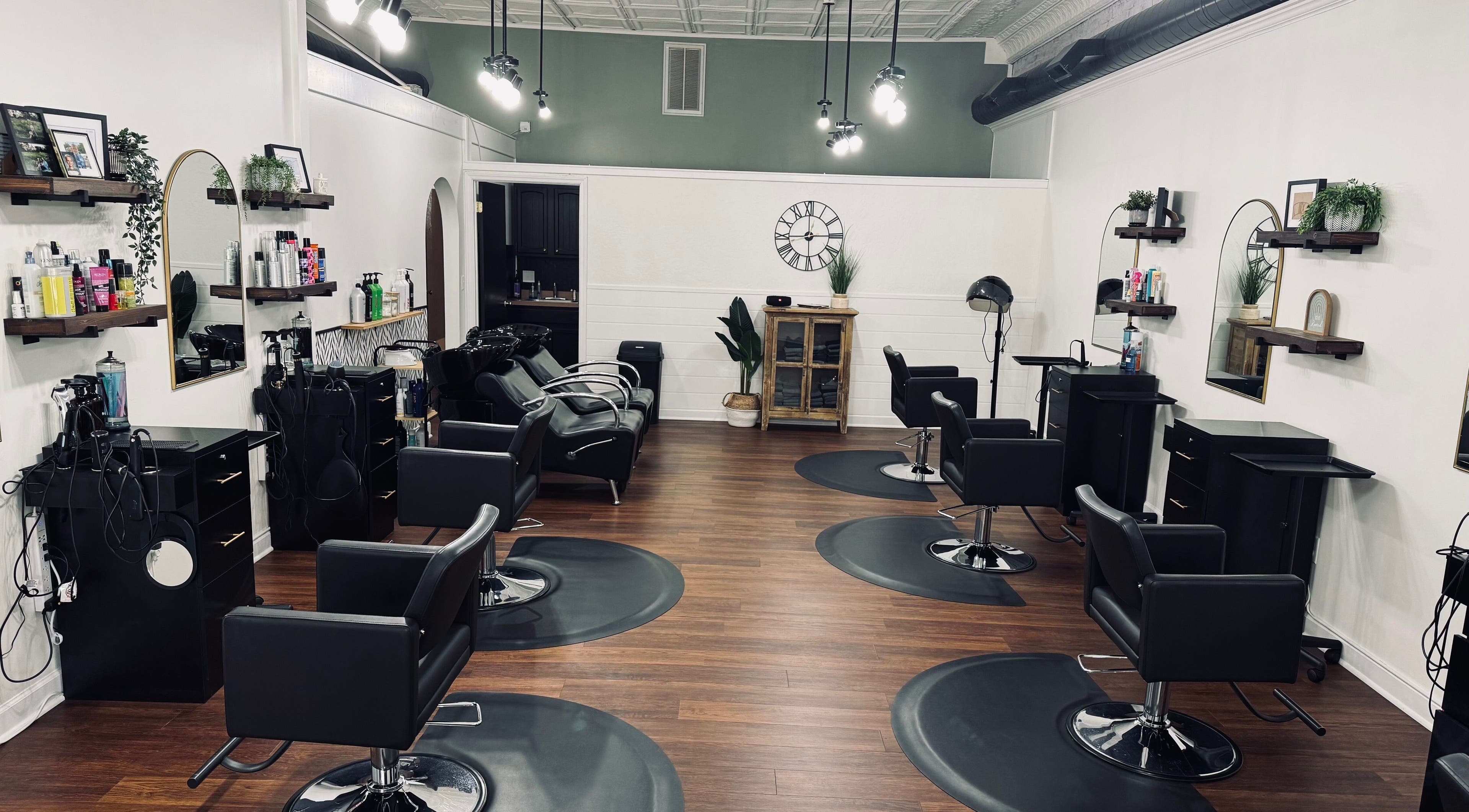 Modern interior of Rooted Salon in Eaton Rapids, Michigan, US, showcasing sleek black styling chairs and mirrors.