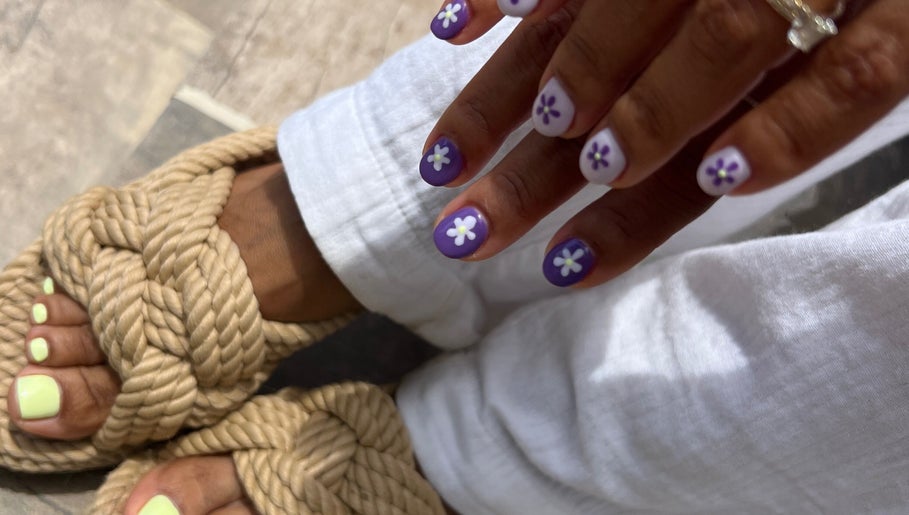 Floral nail art at QWN Esther Beauty Bar, Willemstad, Curaçao, CW with purple nails and braided sandals.