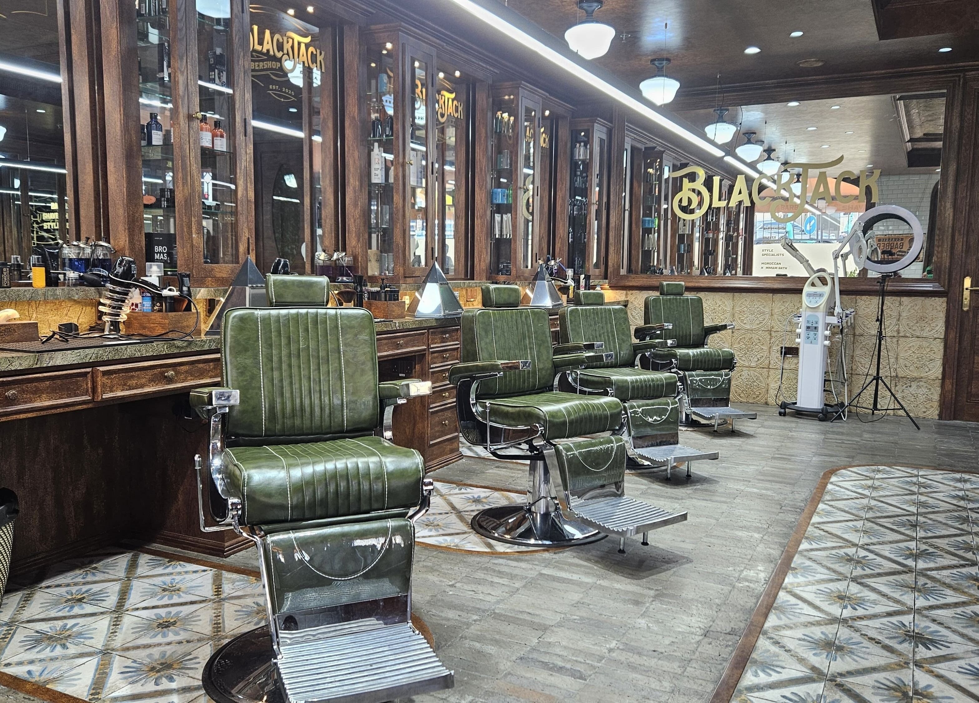 Interior of JBR BlackJack Barbershop, Dubai, Dubai, AE with vintage green barber chairs and wood panel decor.