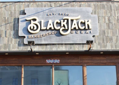 Exterior of JUMEIRAH 3 BLACK JACK BARBER SHOP, Dubai, Dubai, AE with rustic signage and wooden doors.
