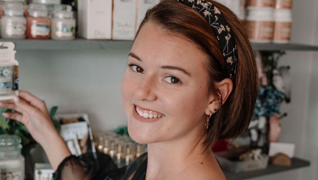 Smiling woman at Smashed Beauty in Jeffreys Bay, Eastern Cape, ZA, surrounded by beauty products on display.