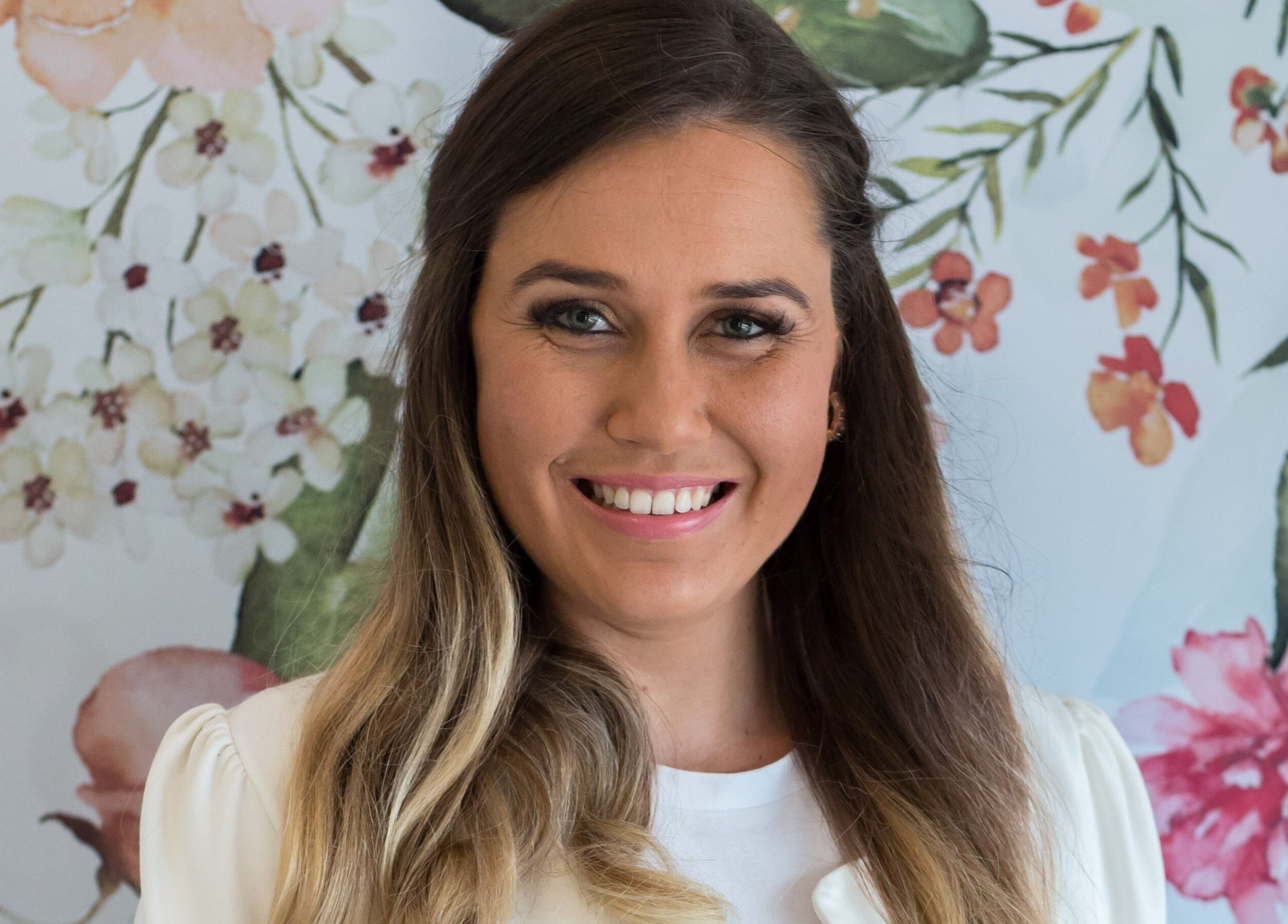Smiling woman at Flourish Salon, Durban North with floral background.