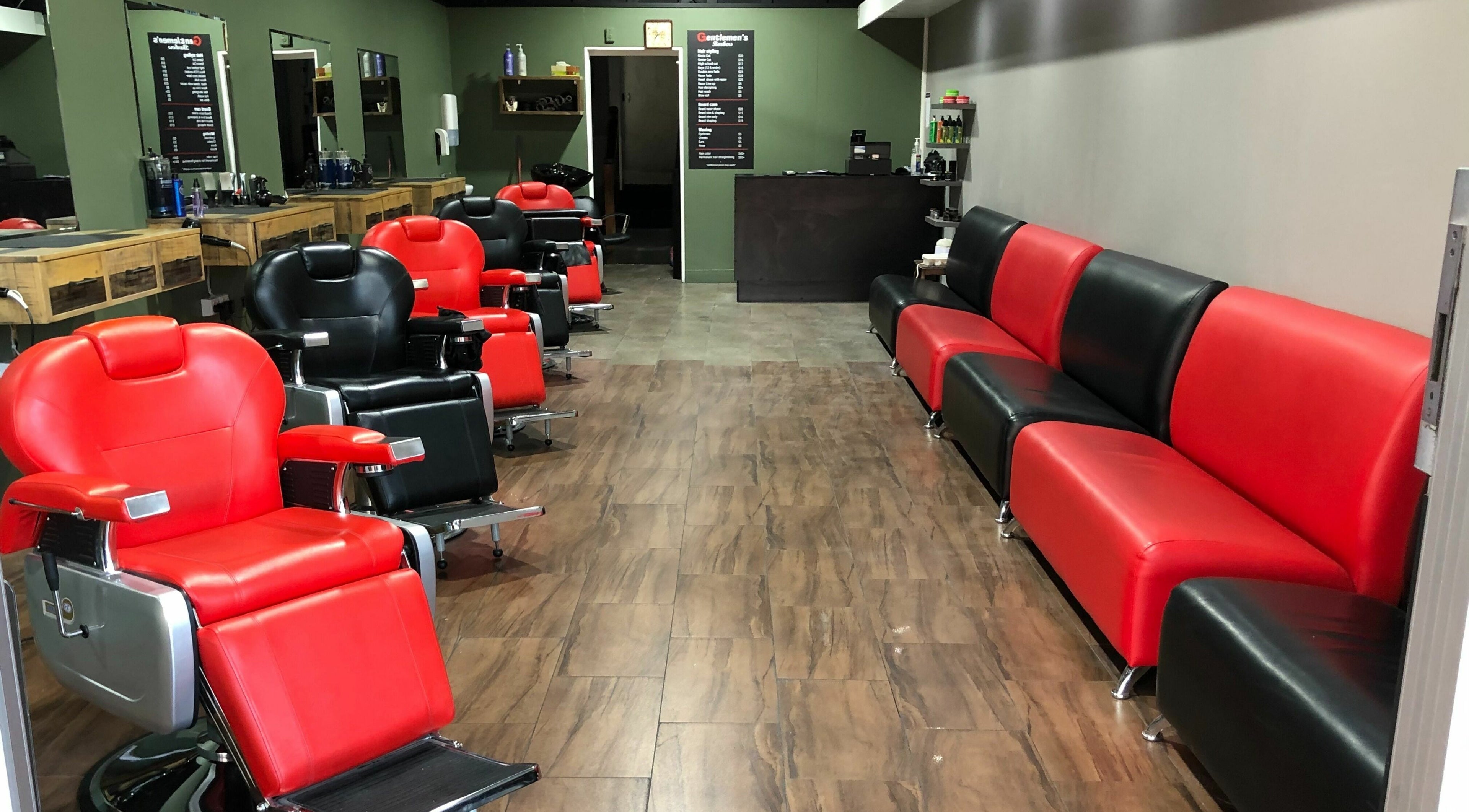 Interior of Gentlemen's Barbers Onehunga in Auckland, NZ, featuring red and black barber chairs and sofas.