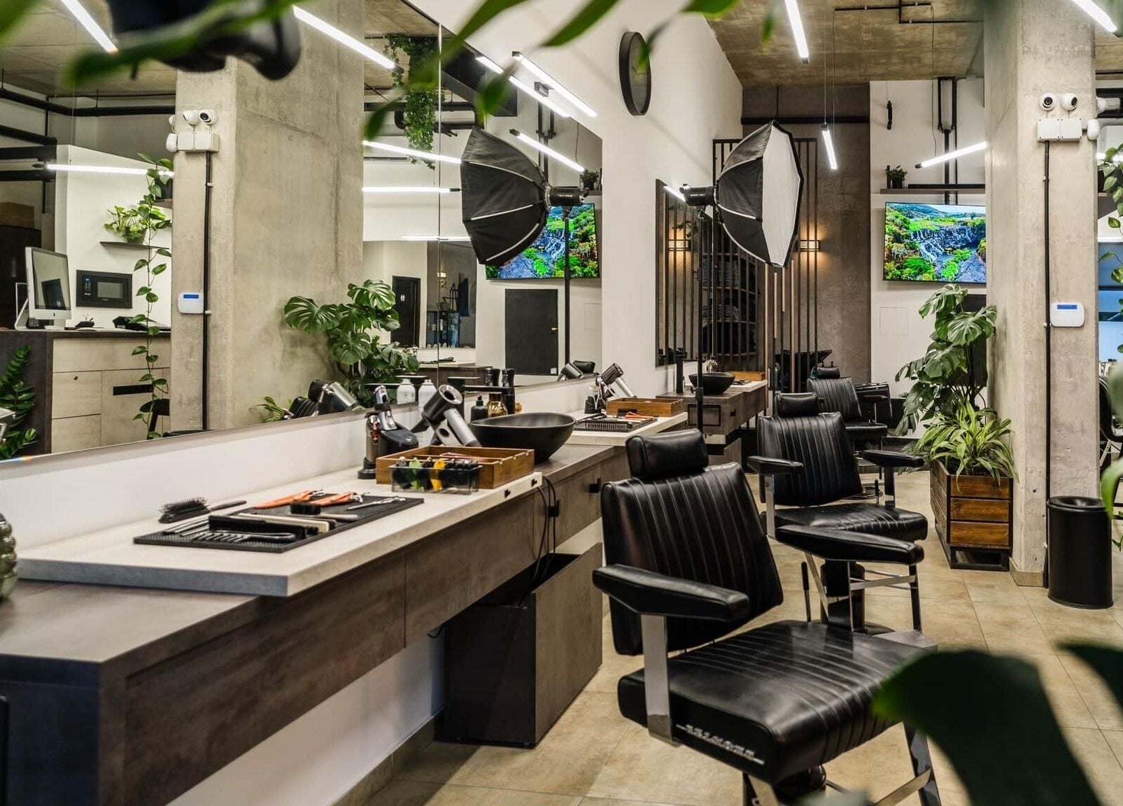 Spacious, modern salon at Initials, Budapest, Magyar, HU featuring stylish black chairs and lush greenery.
