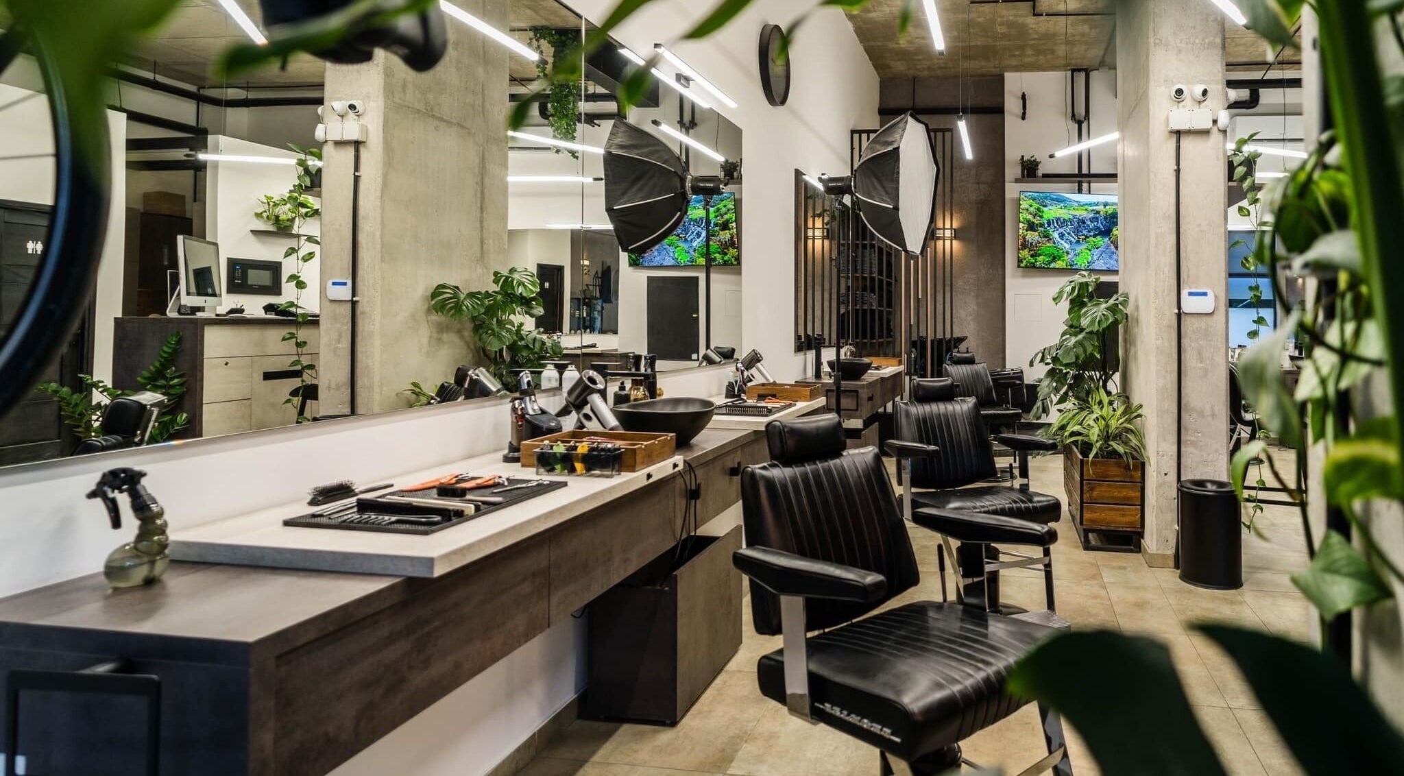 Spacious, modern salon at Initials, Budapest, Magyar, HU featuring stylish black chairs and lush greenery.