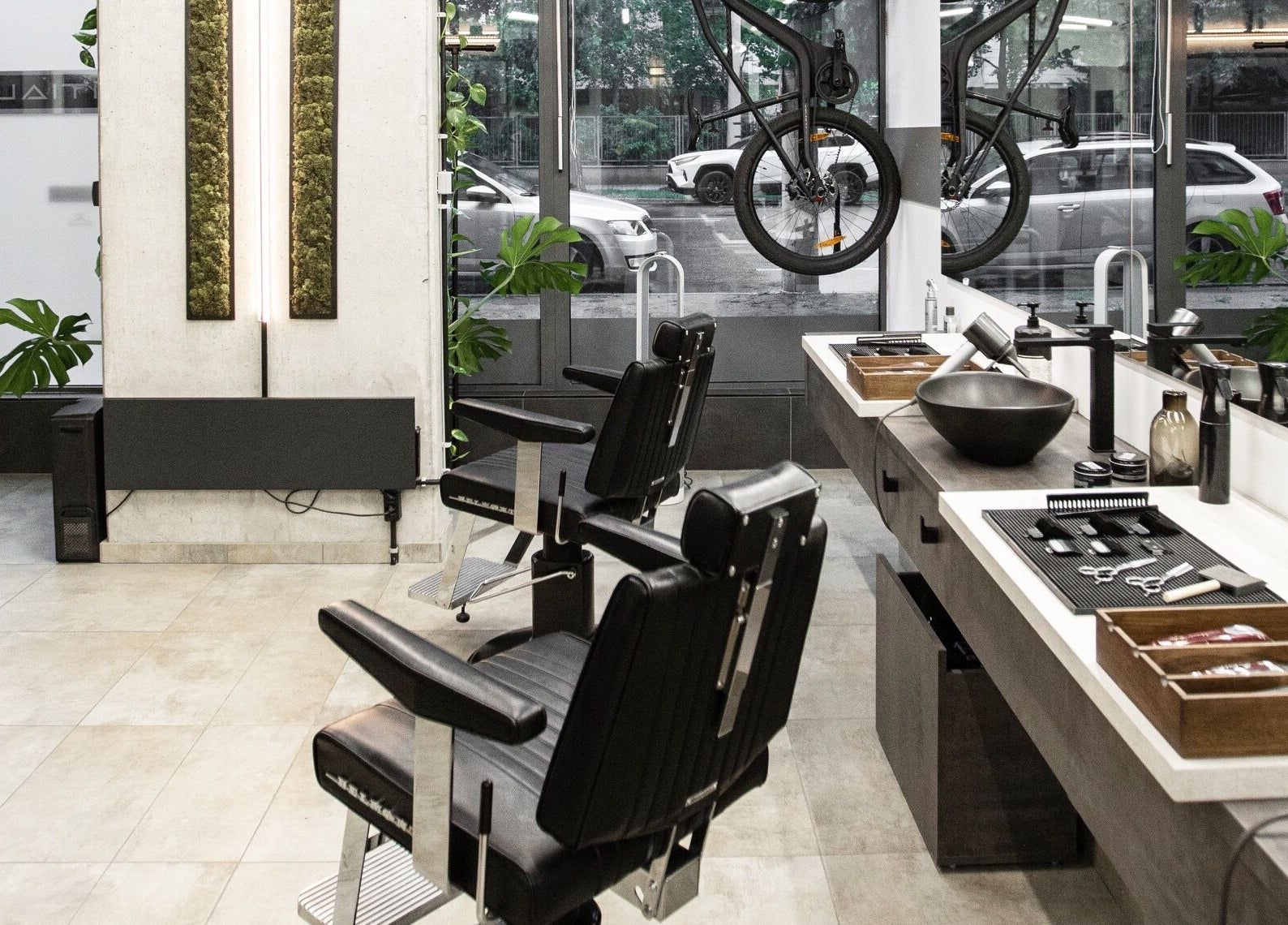 Modern barber stations at Initials in Budapest, Magyar, HU, featuring sleek black chairs and styling tools.